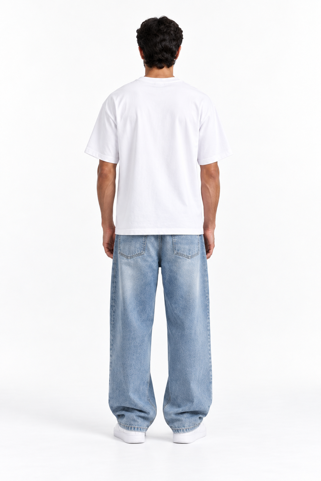 A man viewed from behind wearing a plain white short-sleeve t-shirt and light blue relaxed-fit jeans, standing against a clean white studio background.