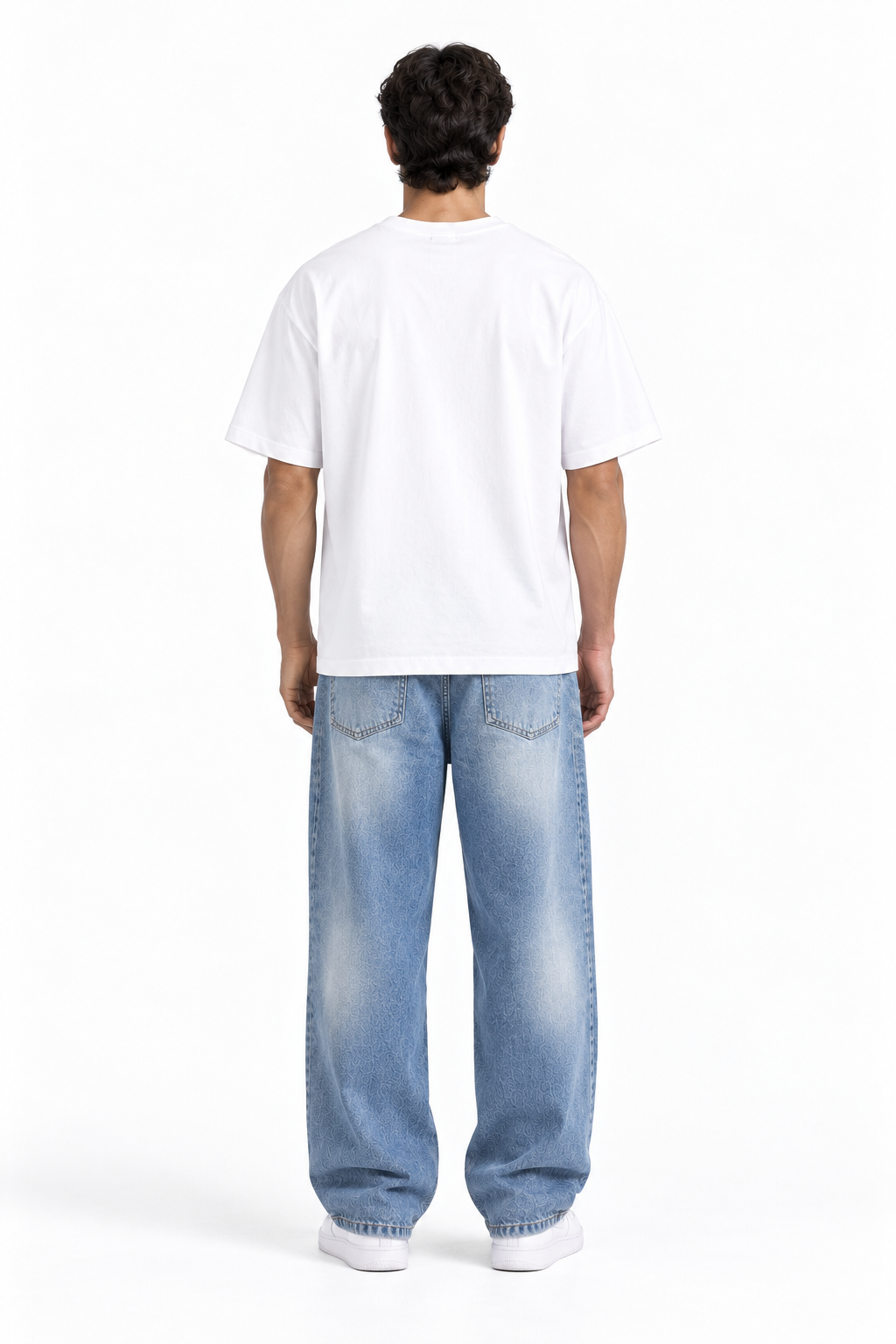A man viewed from behind wearing a white short-sleeve t-shirt, light blue wide-leg jeans, and white sneakers, standing against a plain white studio background.