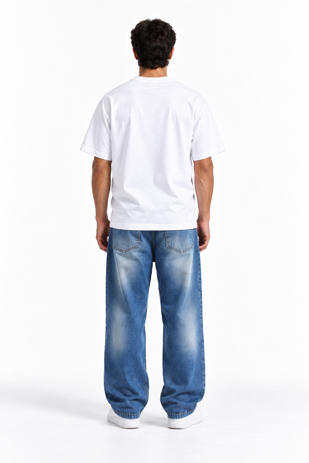A man viewed from behind wearing a plain white short-sleeve t-shirt and loose-fit blue jeans with a faded wash, standing against a clean white studio background.