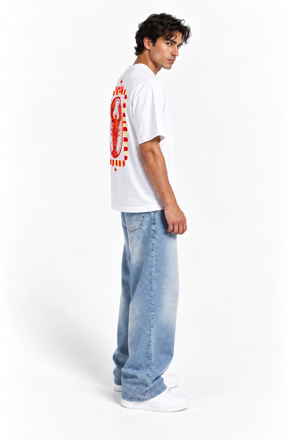 A man wearing a white t-shirt with a red graphic print on the back, paired with light blue jeans and white sneakers, standing against a plain white studio background.