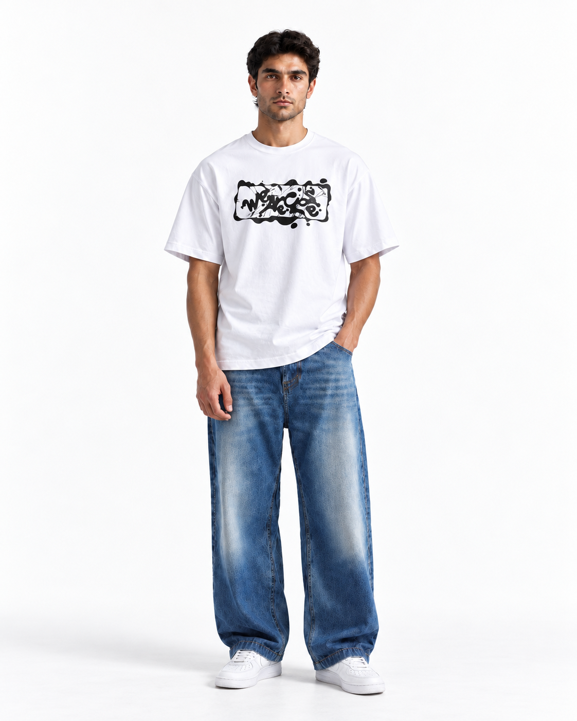 A man modeling a white short-sleeve t-shirt with a black graphic print on the chest, paired with wide-leg blue jeans and white sneakers, against a plain white studio background.