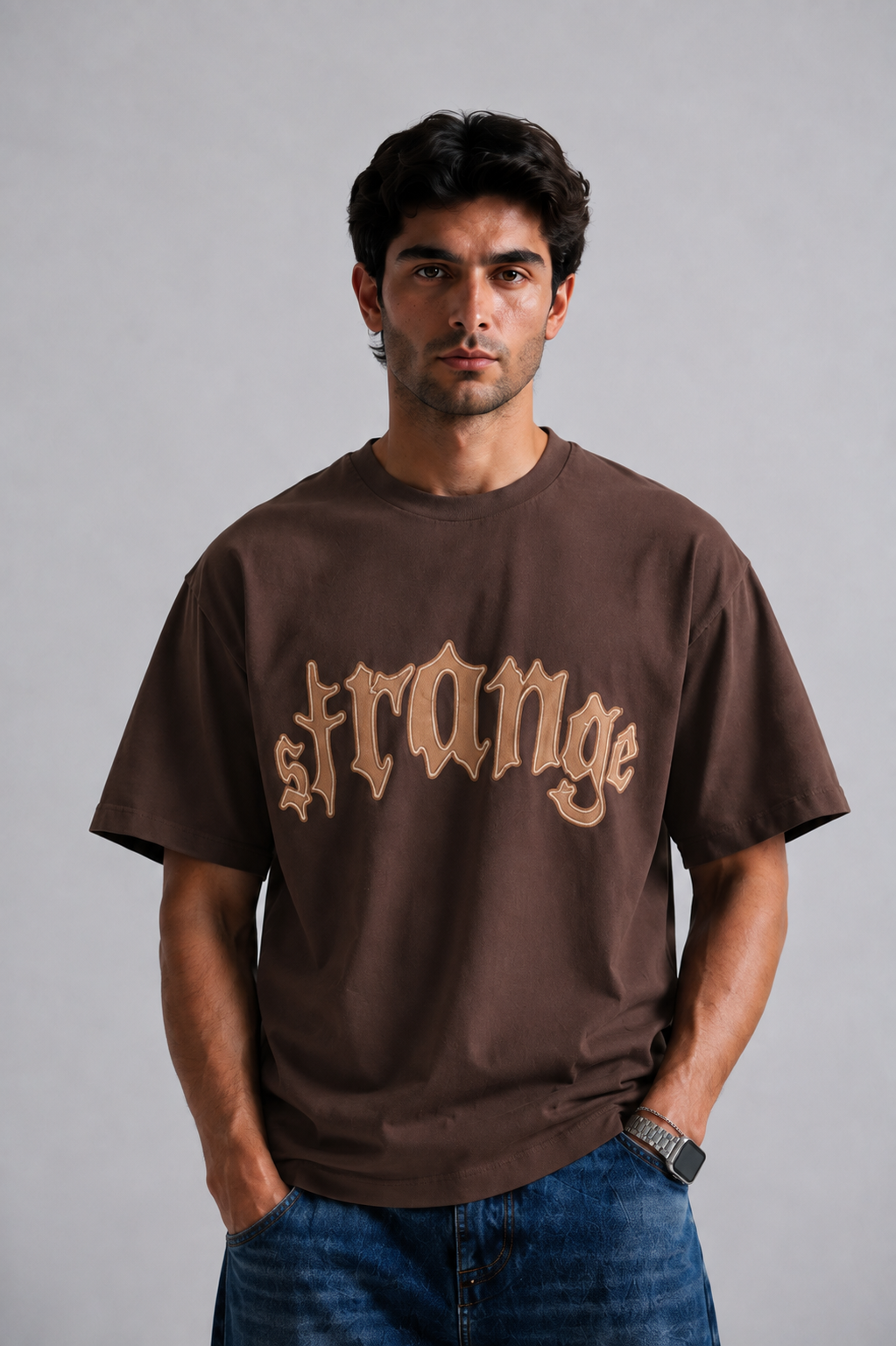 Brown Strange graphic tee styled with baggy jeans